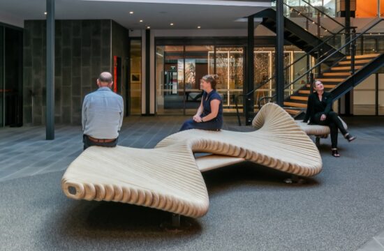 Overhead view of the moveart Climbslide 6.8 in the atrium at Burnie Arts Centre, with people sitting on it beside glowing light-tree sculptures